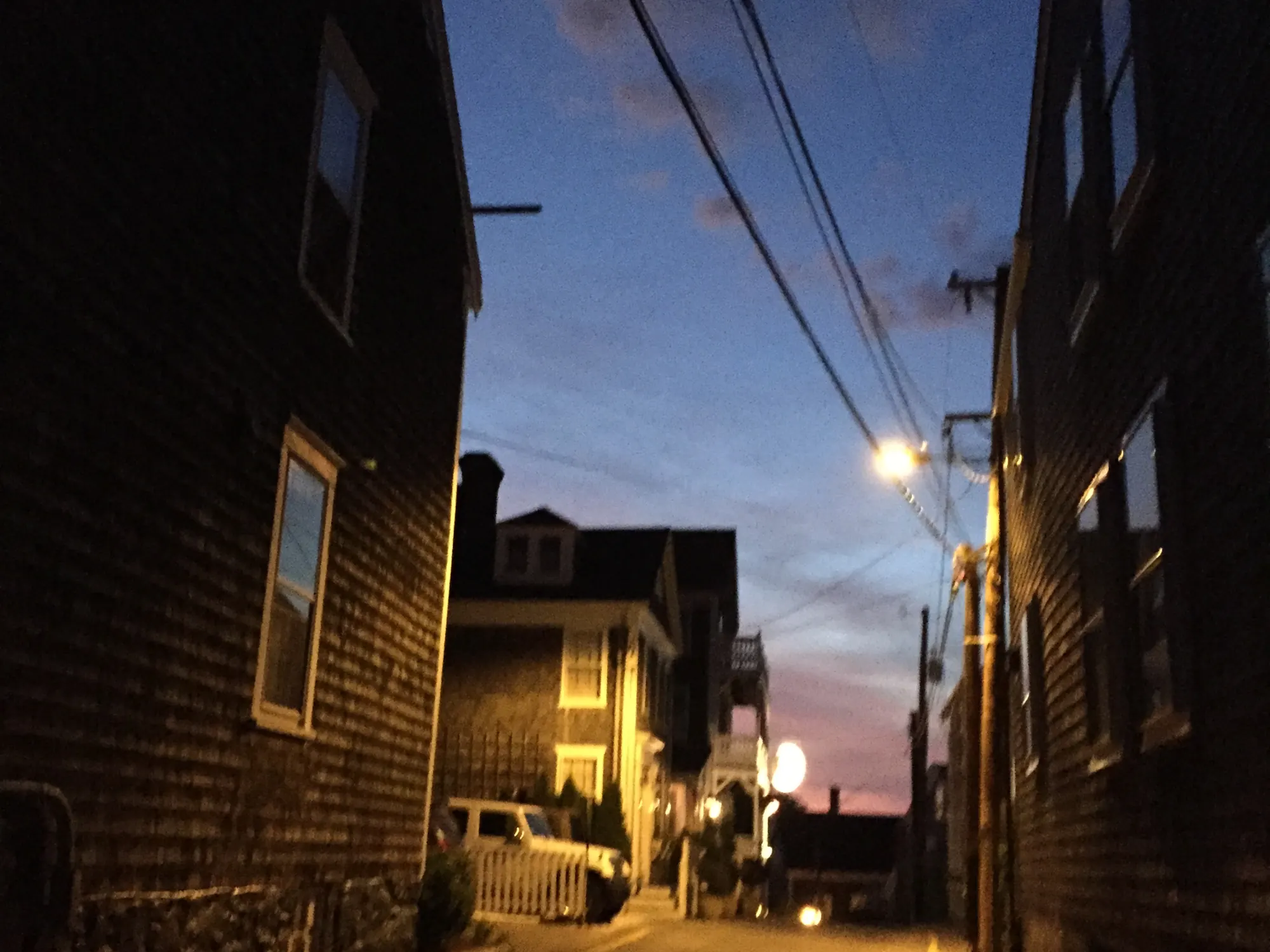Centre Street in downtown Nantucket at dusk, lamplight on the shingled houses