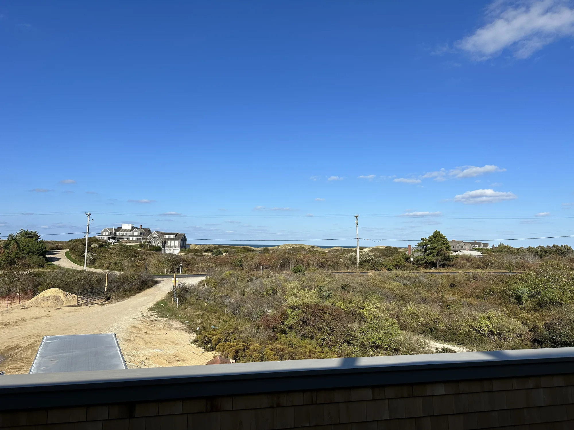 Sandy road running toward the beach past dune-sheltered houses in the Dionis area of Nantucket