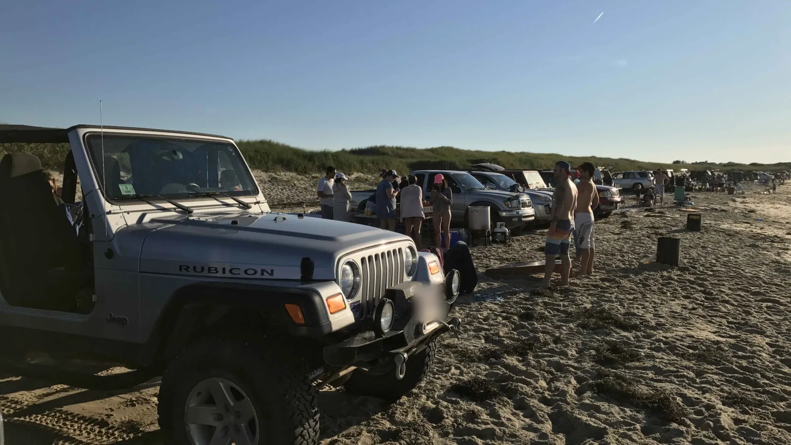A summer evening at 40th Pole on Nantucket: four-wheel-drives parked in a line along the sand, a cookout under way beside them, dune grass behind