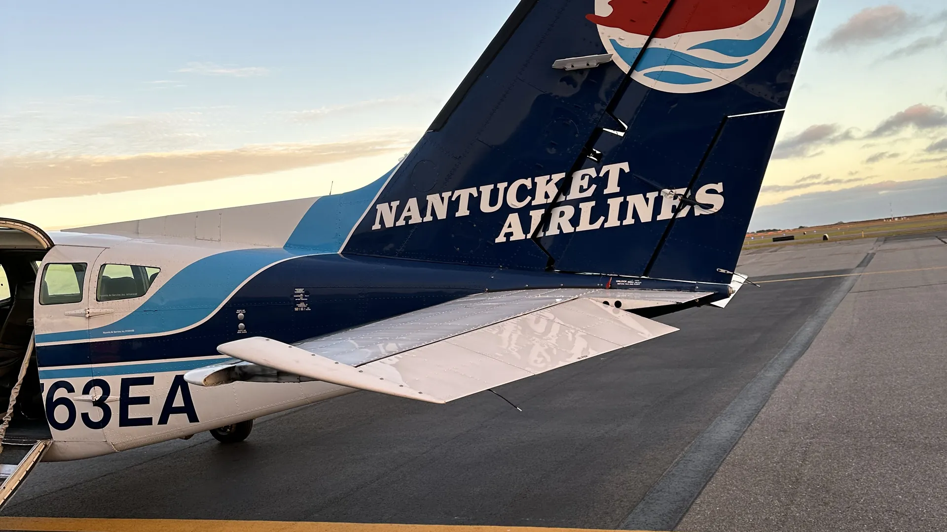 The tail of a Nantucket Airlines plane on the tarmac at Nantucket Memorial Airport at sunset