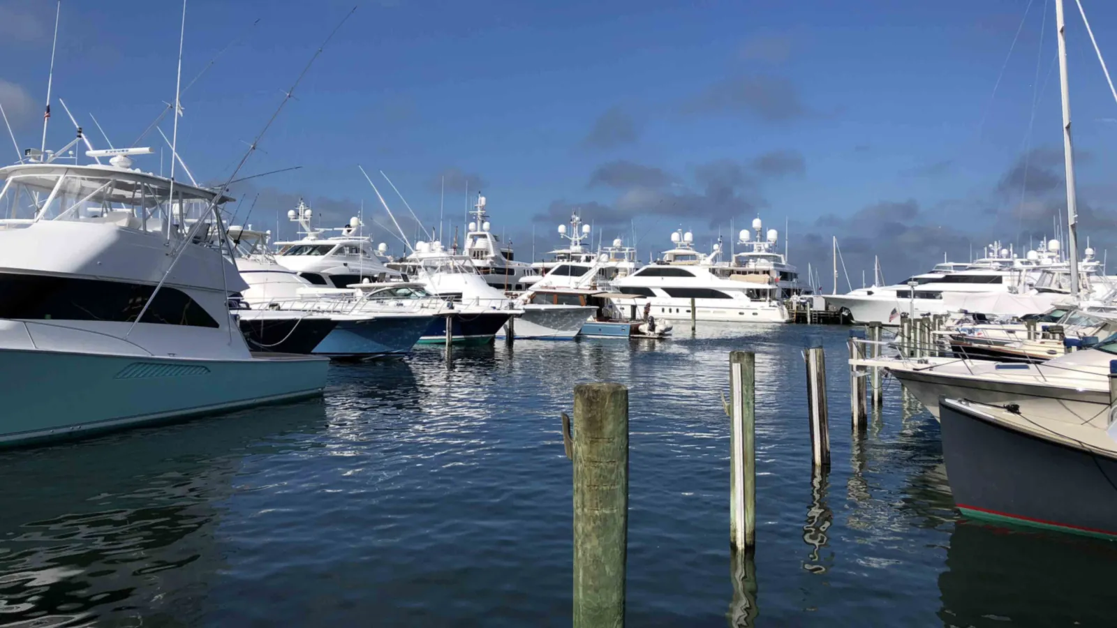 Sportfishers and yachts stern-to at the Nantucket Boat Basin, weathered pilings in the foreground under a summer sky