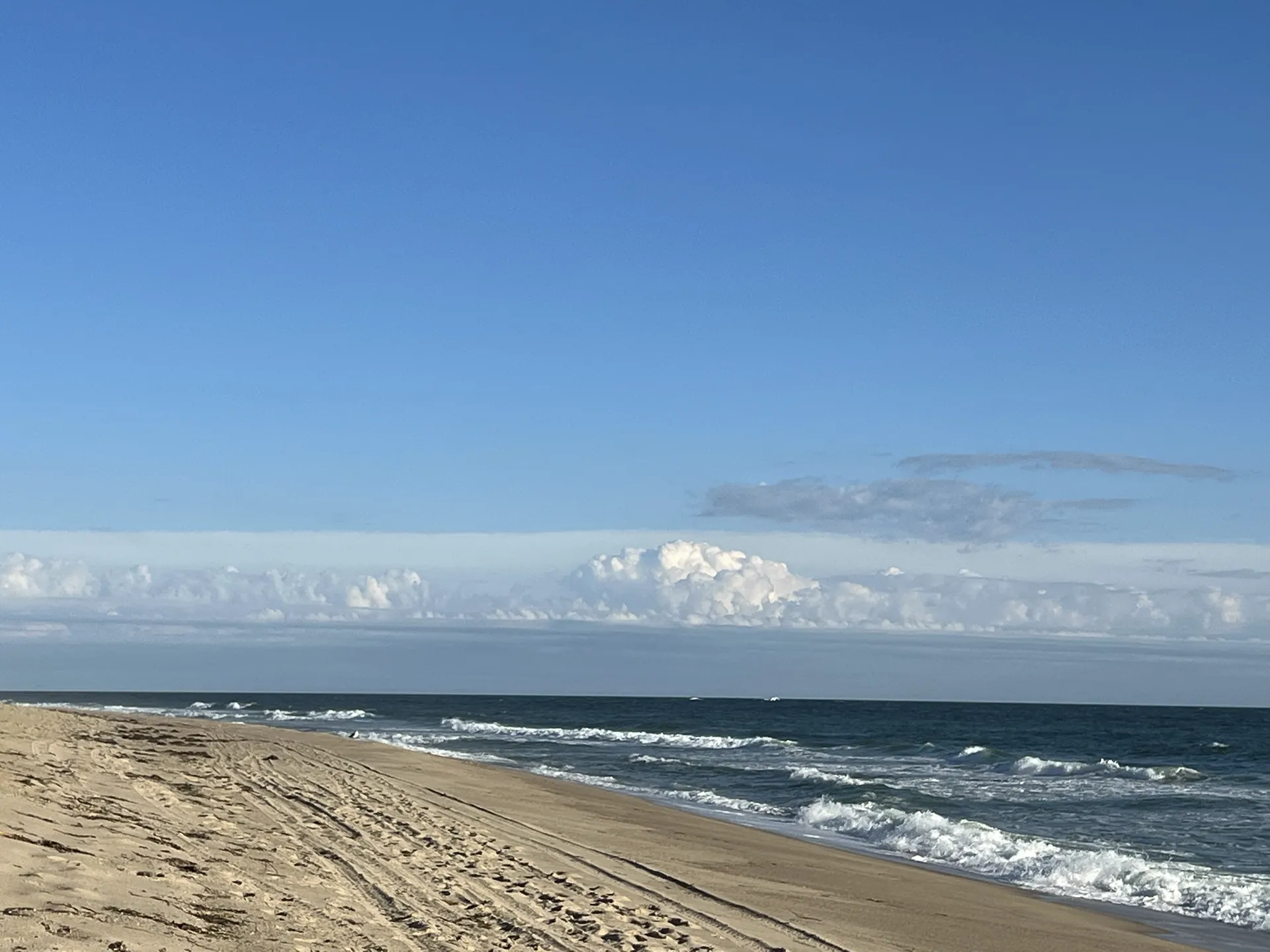 An empty Nantucket south-shore beach under a clear late-September sky, the surf line running to the horizon