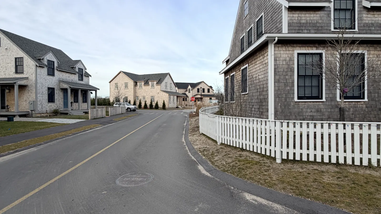 A quiet Nantucket lane of gray-shingled houses and white picket fences under a clear sky