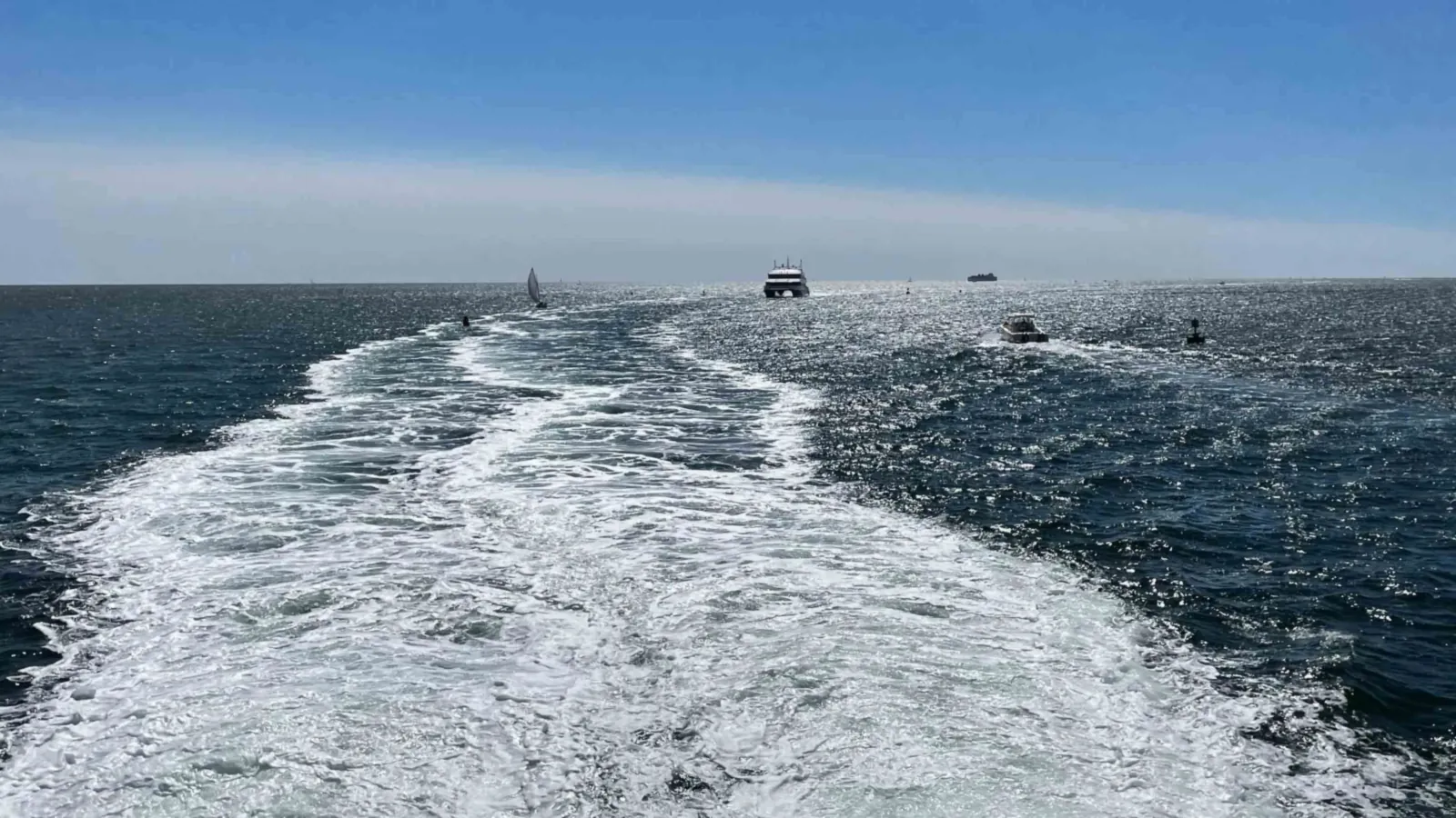 The wake of a Nantucket-bound ferry widening across the Sound, another high-speed boat inbound on the horizon