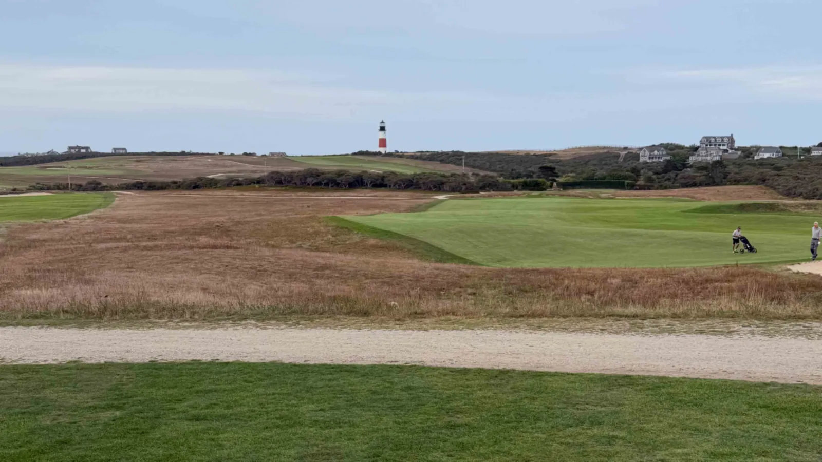 Fescue rough and green fairways at Sankaty Head Golf Club, the red-banded lighthouse rising beyond the course